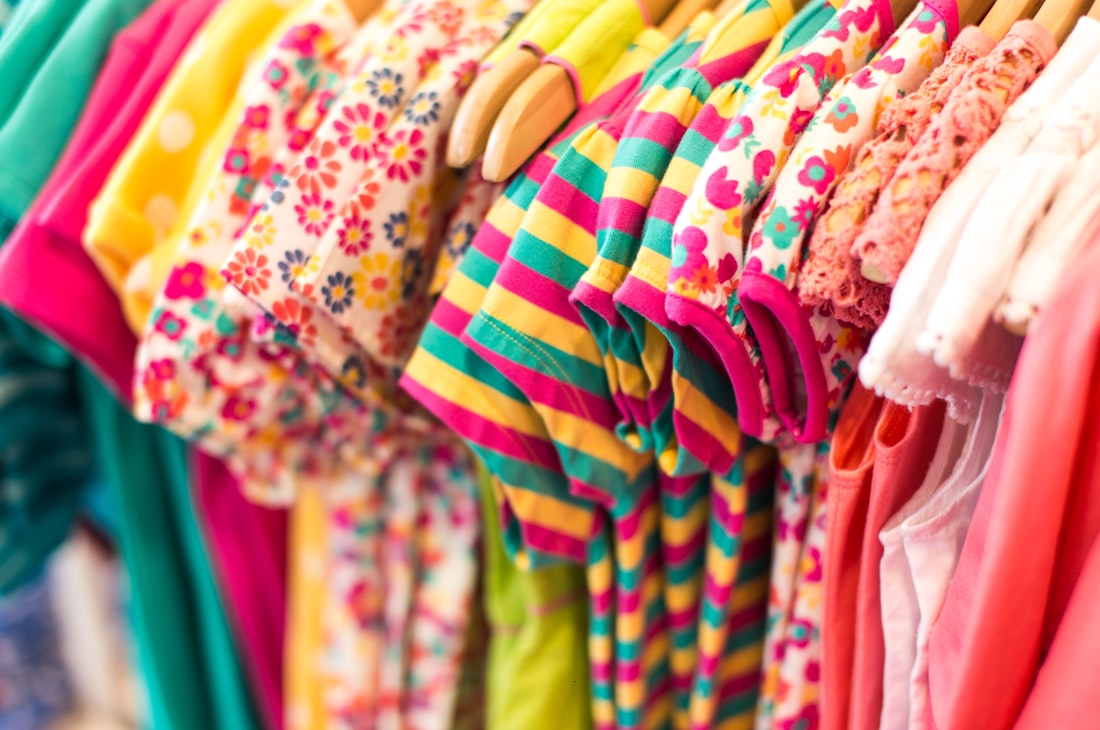 Portant de vêtements d'enfants colorés pour préparer la rentrée sans se ruiner
